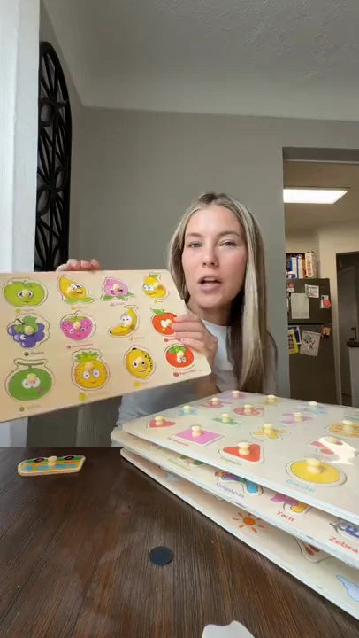 A presenter lifts a fruit-shaped wooden peg piece and fits it back into the matching fruit board