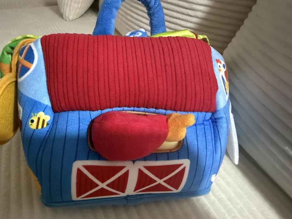 Buyer photo of the same Farm barn on a sofa with the plush rooster visible